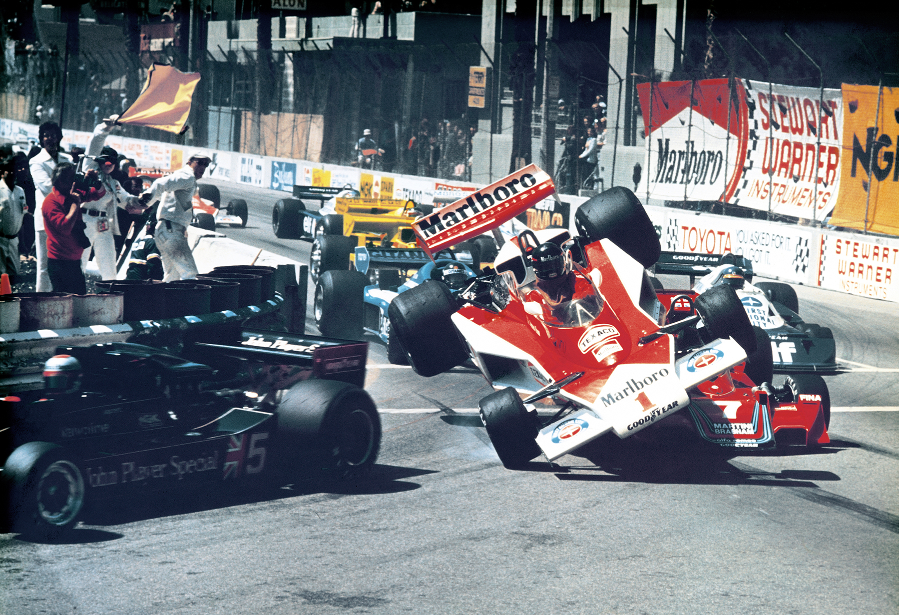 A red racecar collides with another racecar on a track.