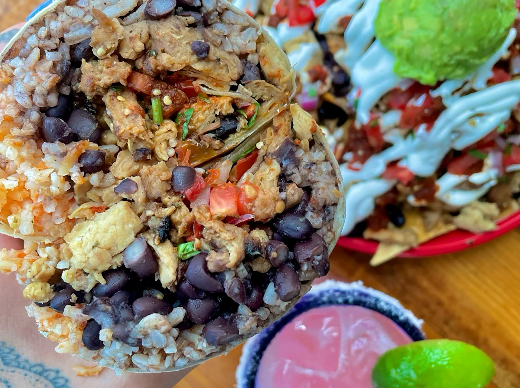 A vegan burrito with meatless chicken is held up. 